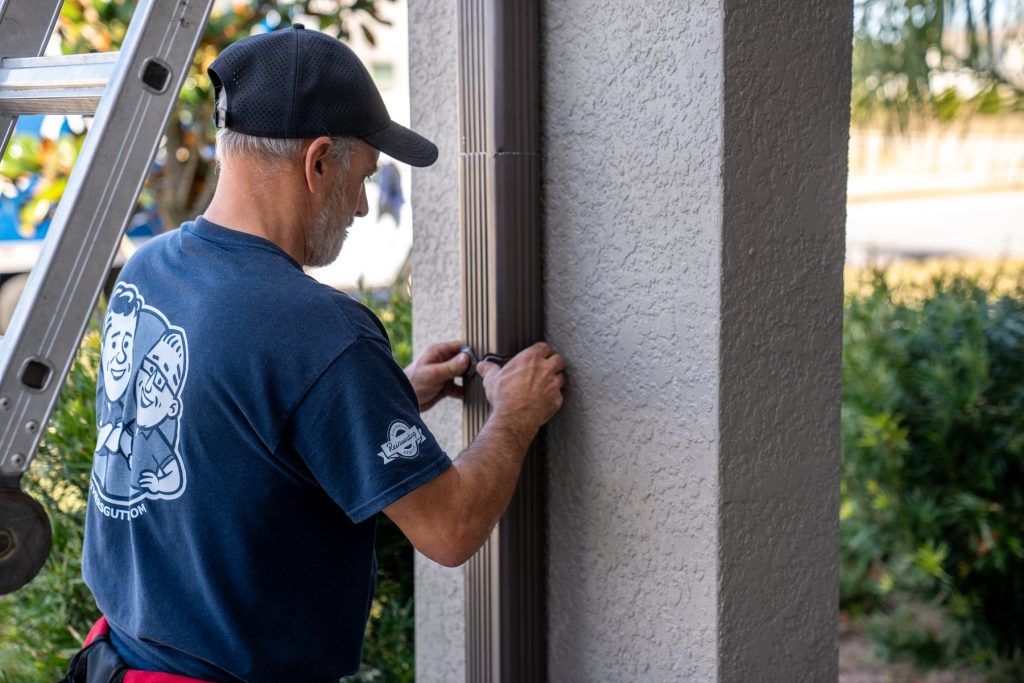 Fastening a downspout strap to the wall