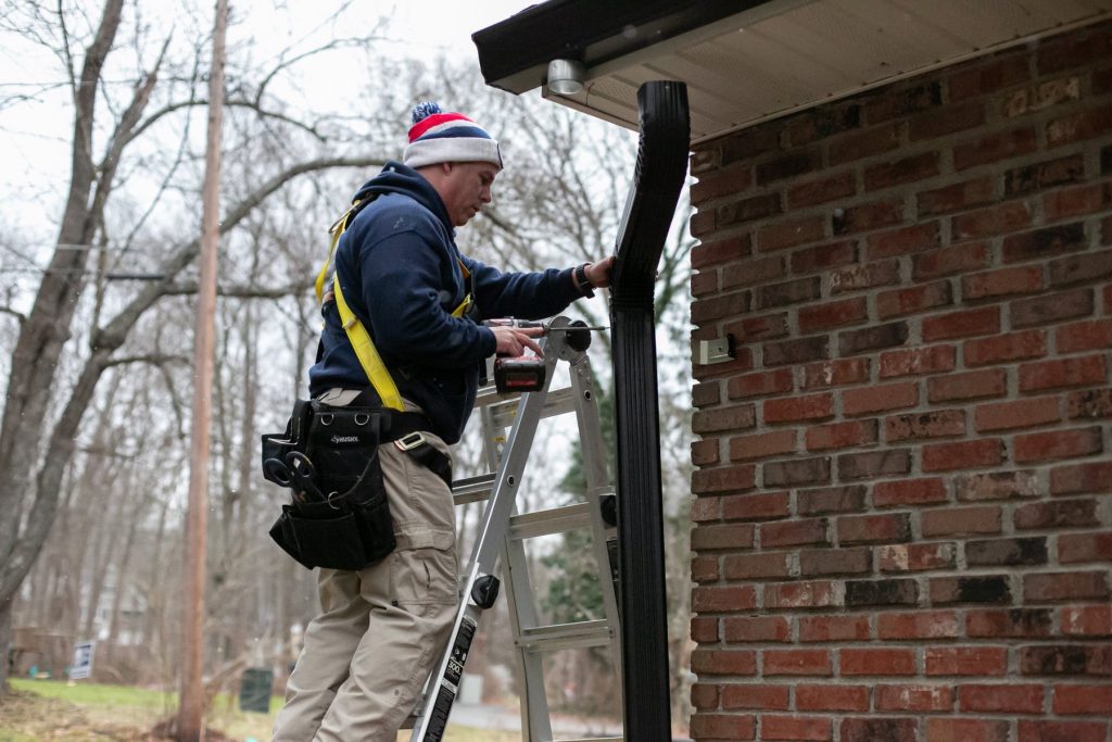 Fitting a dark downspout to the corner of a brick home