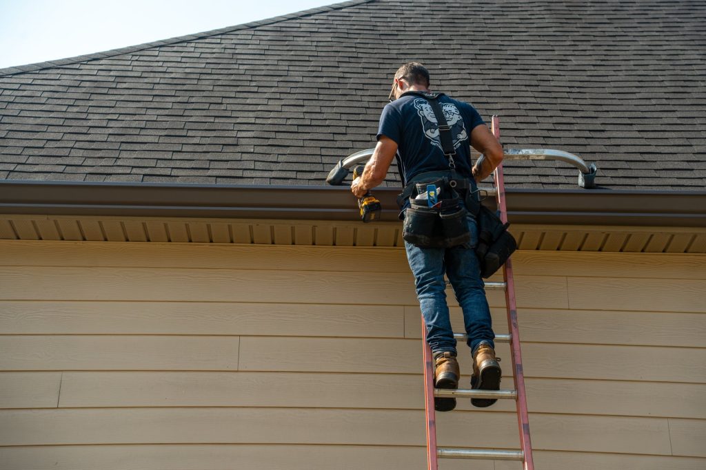Setting a new gutter along the eave from the ladder