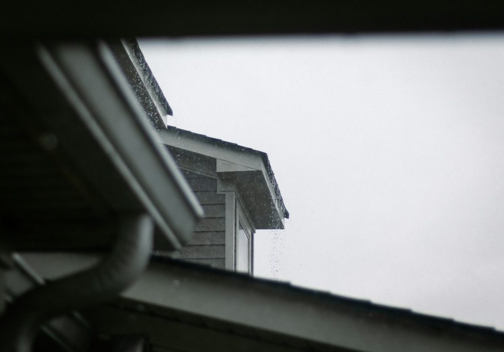 Looking up at a gutter under a dark, rainy sky